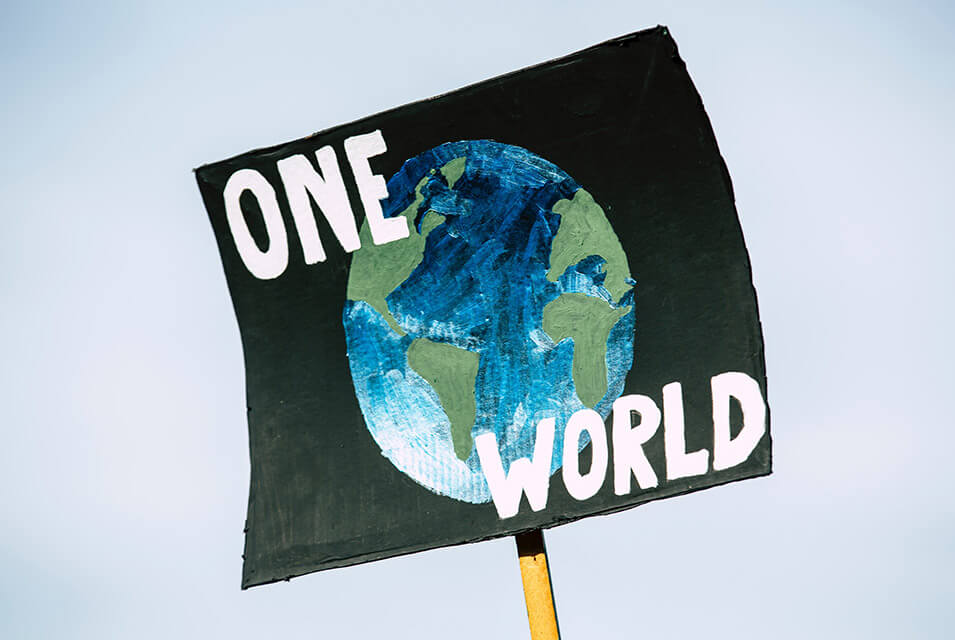 Cartel de protesta con planeta Tierra pintado y la frase One World