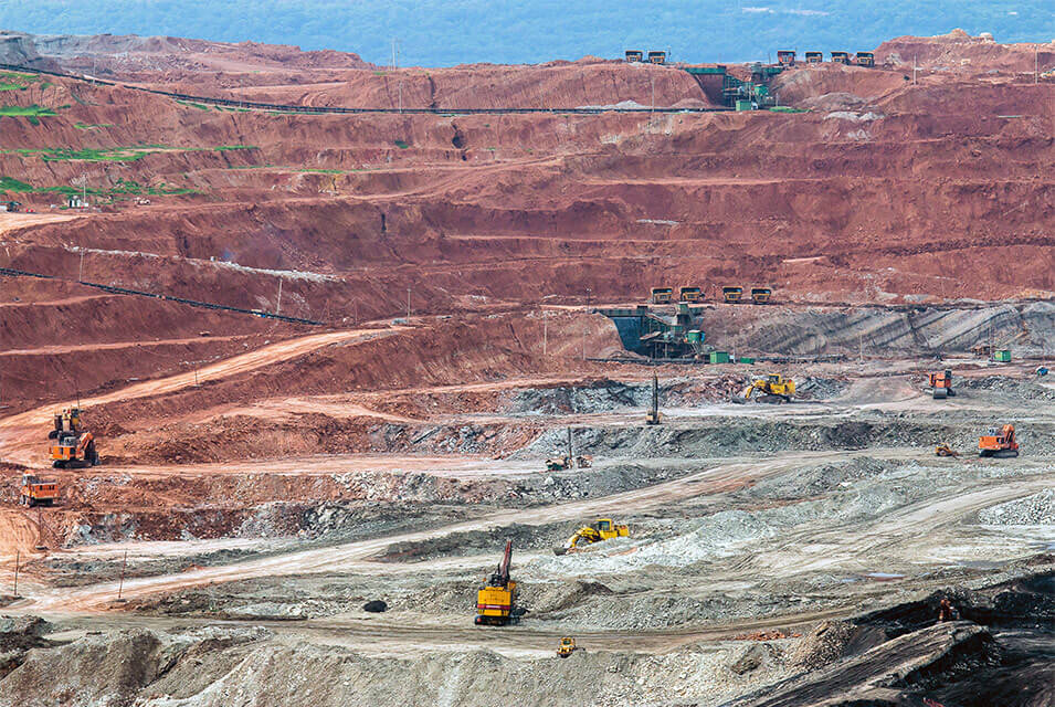Vista lateral de máquinas trabajando en una mina, haciendo referencia al Impacto ambiental de la minería