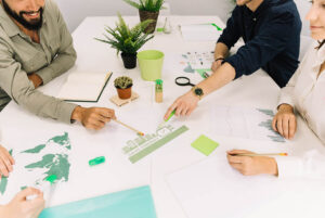 Personas trabajando en escritorio blanco con plantas, planeando estrategias de economía circular para el cuidado del medio ambiente