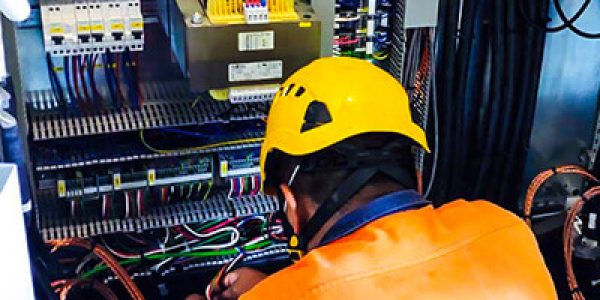 Ingeniero de GTA Ambiental con casco amarillo dando mantenimiento a instalación eléctrica de equipo de reciclaje