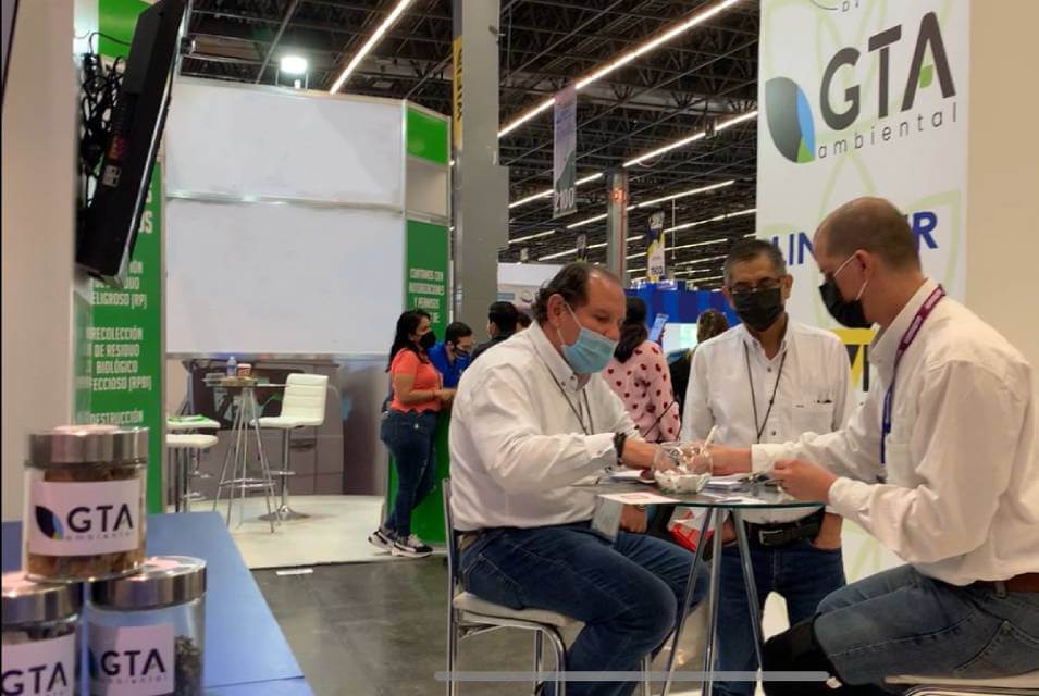 Equipo de GTA Ambiental trabajando en mesa de stand, dentro de la Expo Residuos 2021