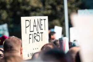 Letrero con el texto "Planet First" en manifestación a favor del medio ambiente, haciendo referencia a la mitigación del cambio climático
