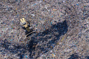 Concepto de Zero Waste to Landfill representado por vista aérea de máquina pala de ruedas en medio de un vertedero de basura